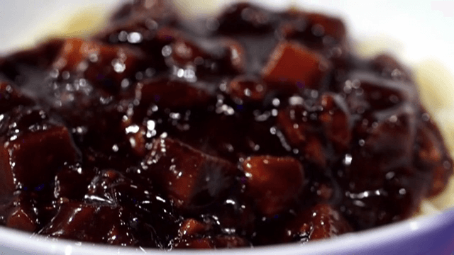 Pouring Black Bean Sauce over noodles