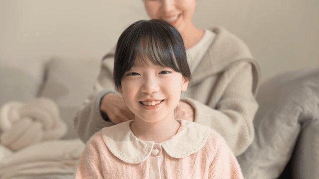 머리를 손질받으며 웃고 있는 아이