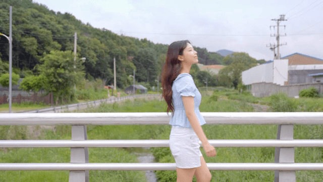 시골 다리 위를 걷는 여성