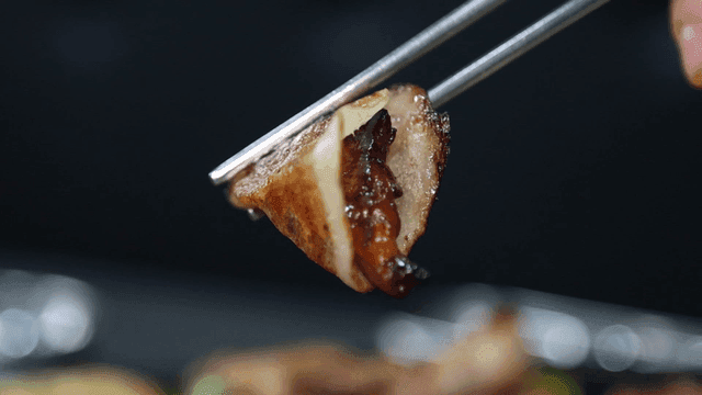 Grilled pork belly held with chopsticks