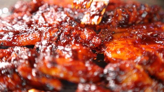 타오르는 숯불 위 그릴에서 지글지글 구워지는 양념고기