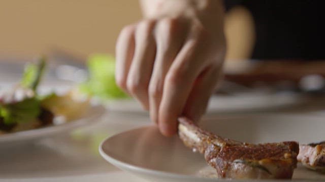 Person Dining on Lamb Chops and Salad