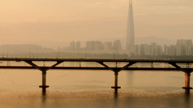 Bridge over a river with a city skyline at sunset