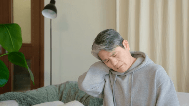 실내에서 목을 마사지하는 노인