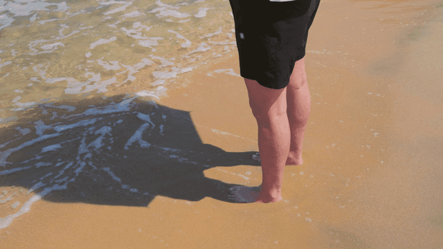 파도가 밀려오는 모래사장에 서 있는 사람