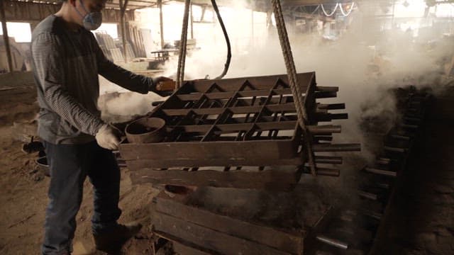 Worker handling metal molds in a factory