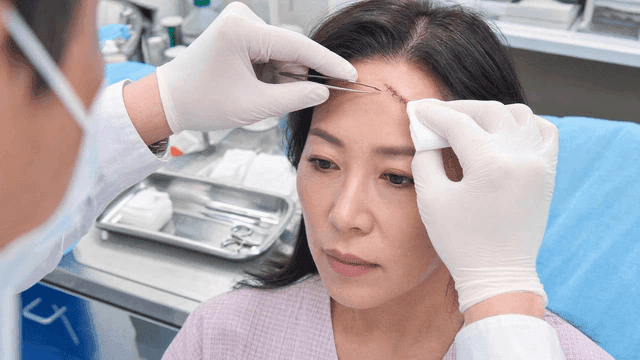 Doctor treating patient's forehead wound