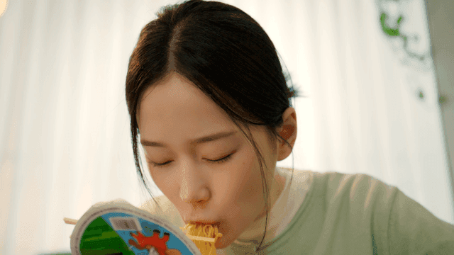 Woman eating cup ramen at home