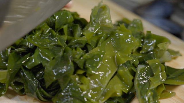Cutting fresh seaweed with a knife in the kitchen
