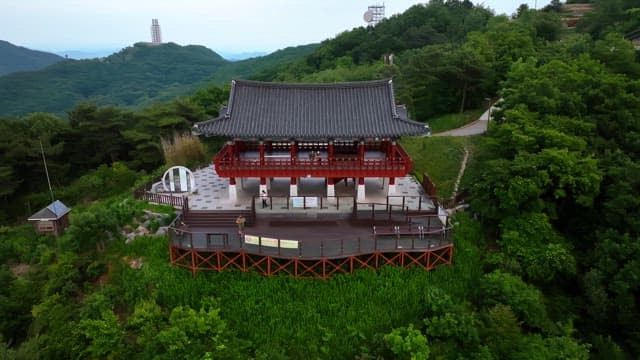 Traditional Korean pavilion on top of a green mountain