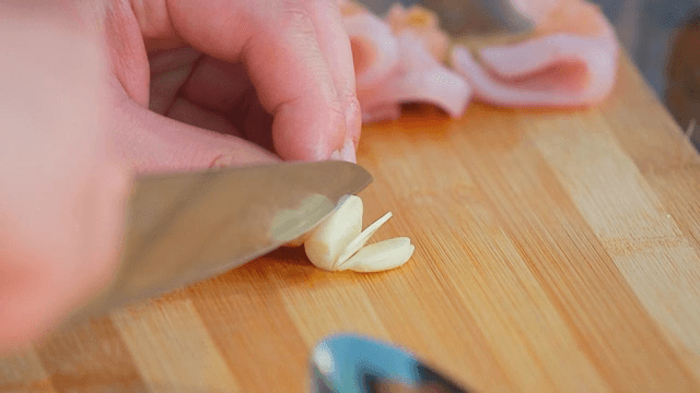 나무 도마 위에서 마늘을 자르는 모습