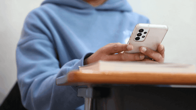 Student using smartphone at his desk