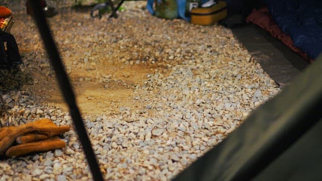 Camper tying shoes on a gravel campsite in early morning