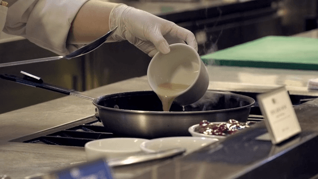 Chef pouring sauce into a hot pan