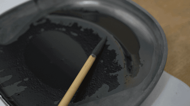 Brush placed on tray containing black ink