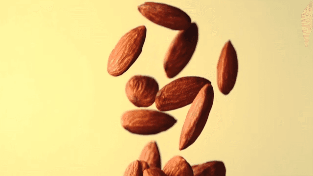 Almonds falling in slow motion against a yellow background