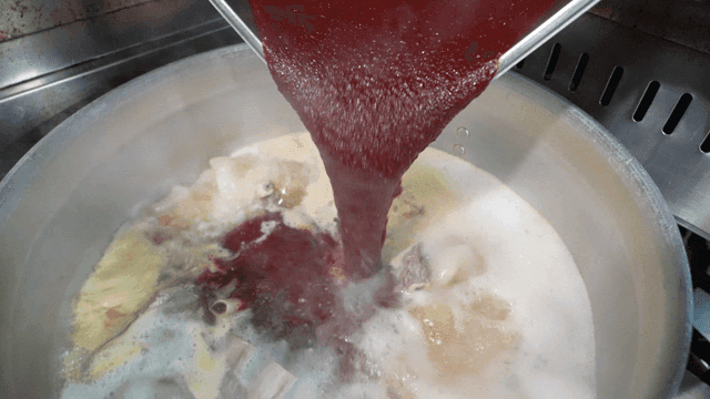 Red sauce poured into boiling pot