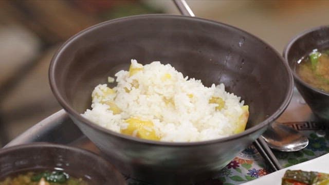 Steaming bowl of rice with chestnuts and spinach soup