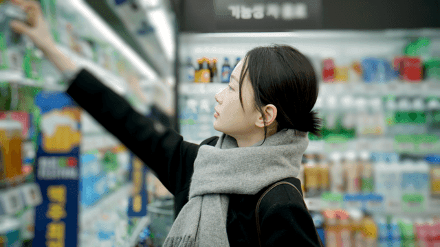 Woman shopping for canned beer at supermarket