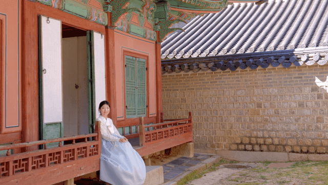 Woman in hanbok sitting at a traditional house
