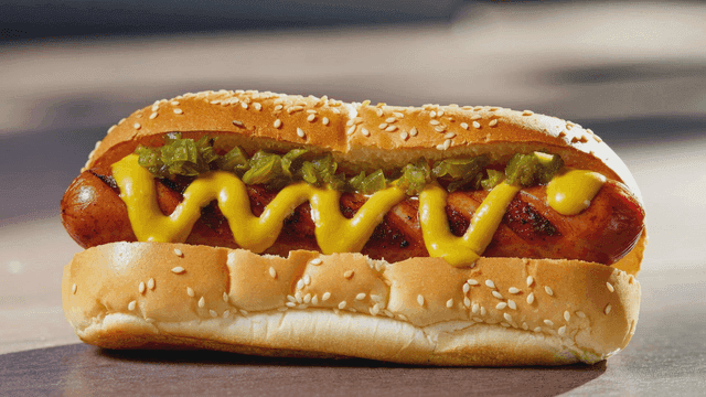 Hot dog topped with mustard and relish.