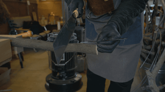 작업실에서 톱으로 나무를 자르는 목공예가