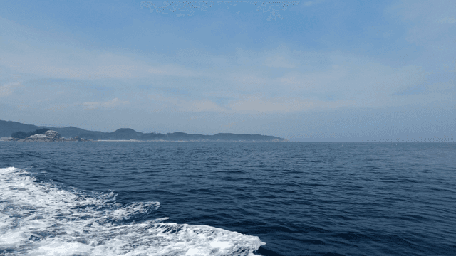 A boat sailing on the open sea with distant islands