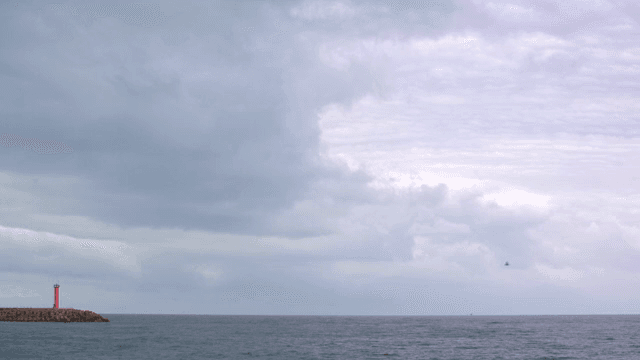 흐린 날의 바다 위 빨간 등대