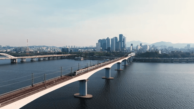 Train passing over city skyline and bridge over river