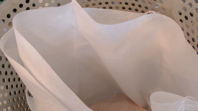 금속 용기 내부에 있는 천 거름망에 생고기를 넣는 모습