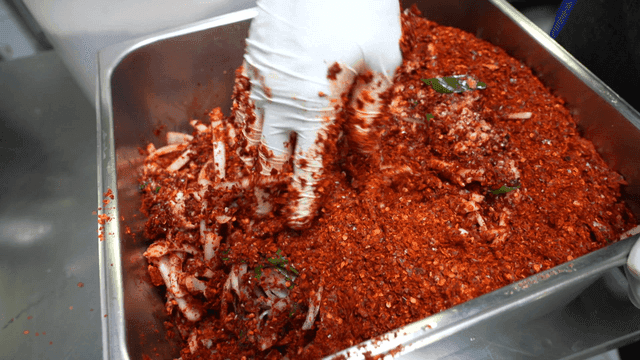 금속 트레이에서 김치 속재료를 섞는 모습