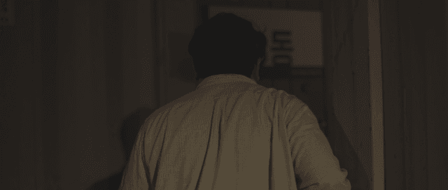 Man walking through a dimly lit hallway