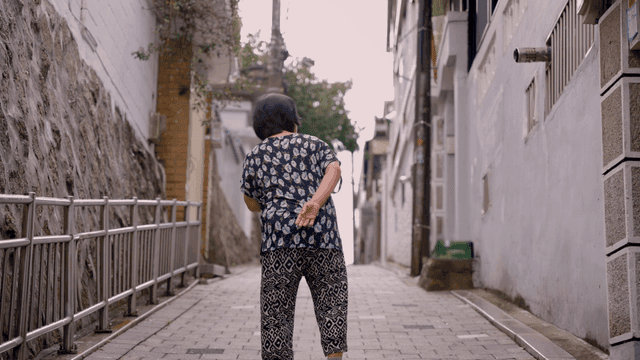 An elderly woman walking down an alley