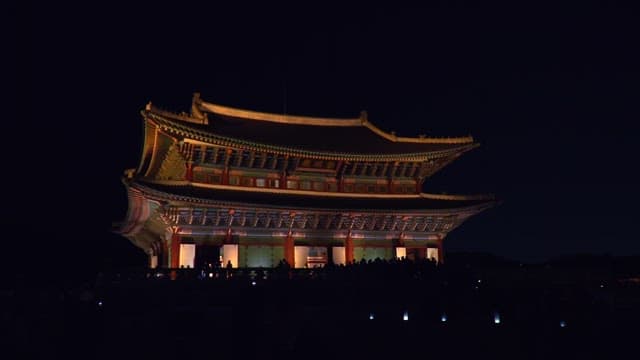 Magnificent Gyeongbokgung Palace with its lights on at night, filled with tourists