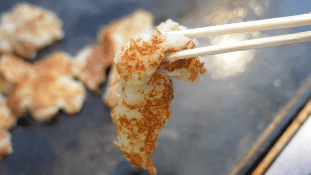 Sizzling potato pancake picked up with chopsticks