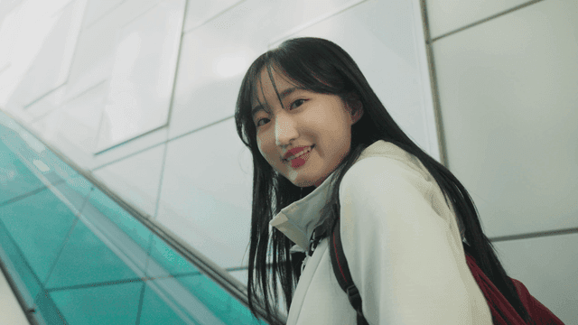 에스컬레이터를 타고 올라가며 미소짓는 여성