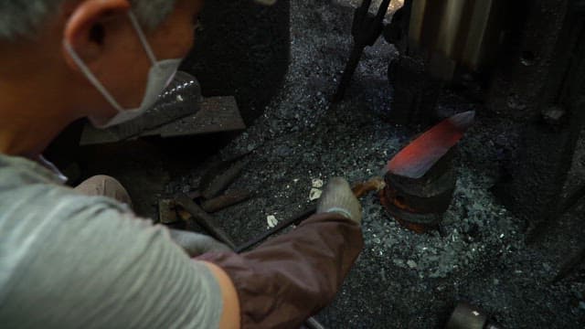 Craftsman forging a heated metal blade