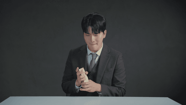 만족스러운 표정으로 돈 냄새를 맡는 남자