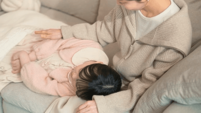 Woman gently patting their sleeping child
