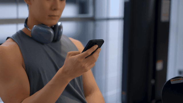 헬스장에서 목에 헤드셋을 차고 스마트폰을 사용하는 남성