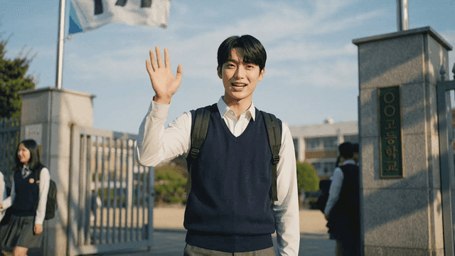 Male student waving his hand at school's main entrance