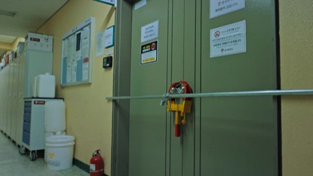 빌딩 복도에 쌓인 의자들과 굳게 잠긴 문