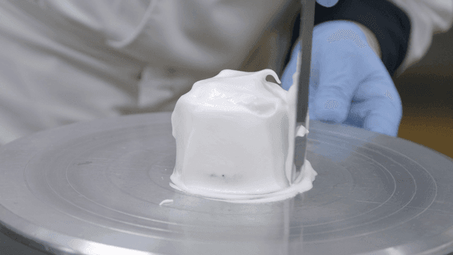 Baker spreading cream on chocolate cake