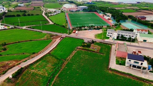 View of coastal village with green fields and soccer field