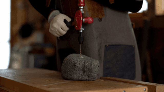 손 드릴로 돌을 뚫는 사람