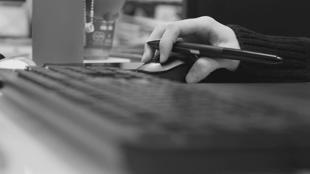 컴퓨터 마우스 위 펜를 잡고 있는 손