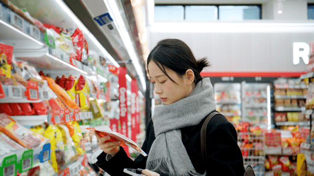 Young woman shopping for ham at supermarket