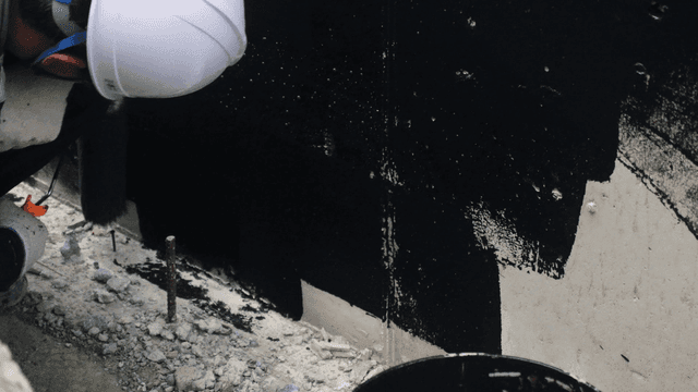 검은 페인트로 벽을 칠하는 작업자