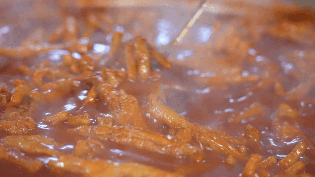 Spicy chicken feet in broth stirred with ladle