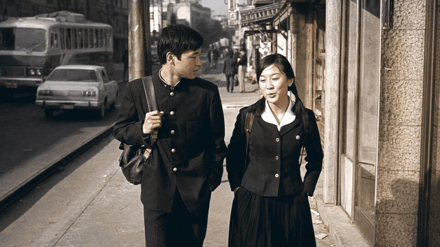Two students walking and talking on city street in 1970s